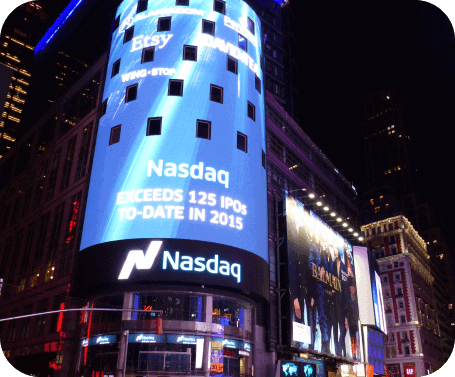 the nasdaq stock exchange is lit up at night.